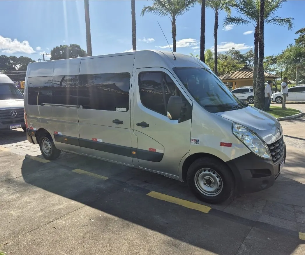 Van da Adário TÁXI E TURISMO estacionada entre coqueiros na entrada de um resort