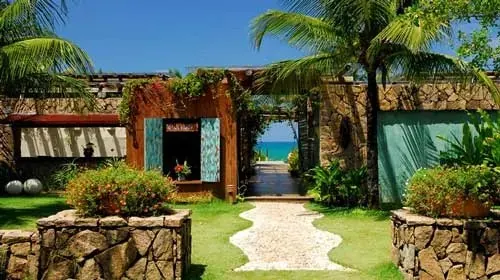 Entrada de pedra e madeira com jardim e caminho de pedras para o mar